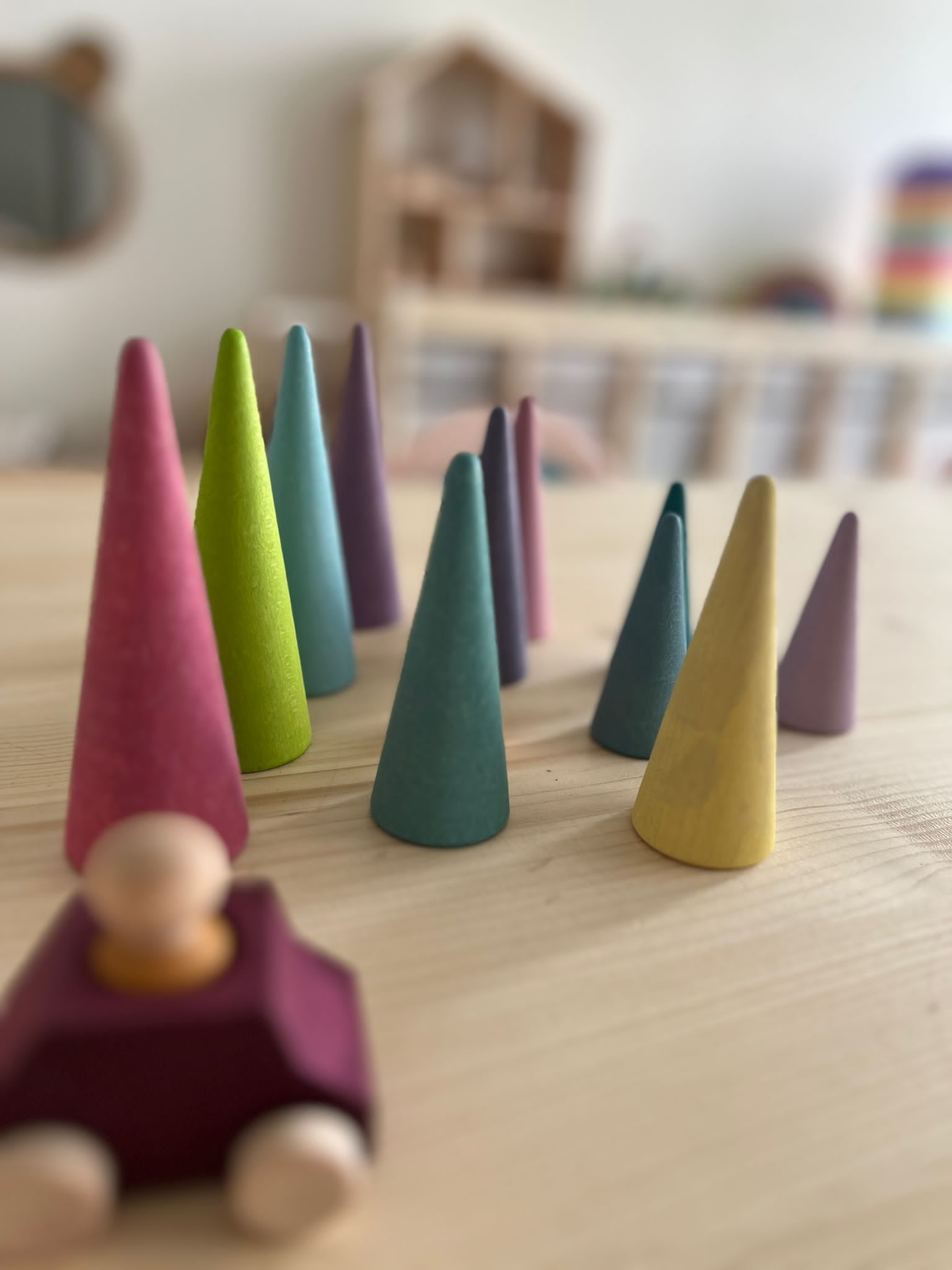 Bunte Holzkegel und ein Holzmännchen in einem Spielzeugauto