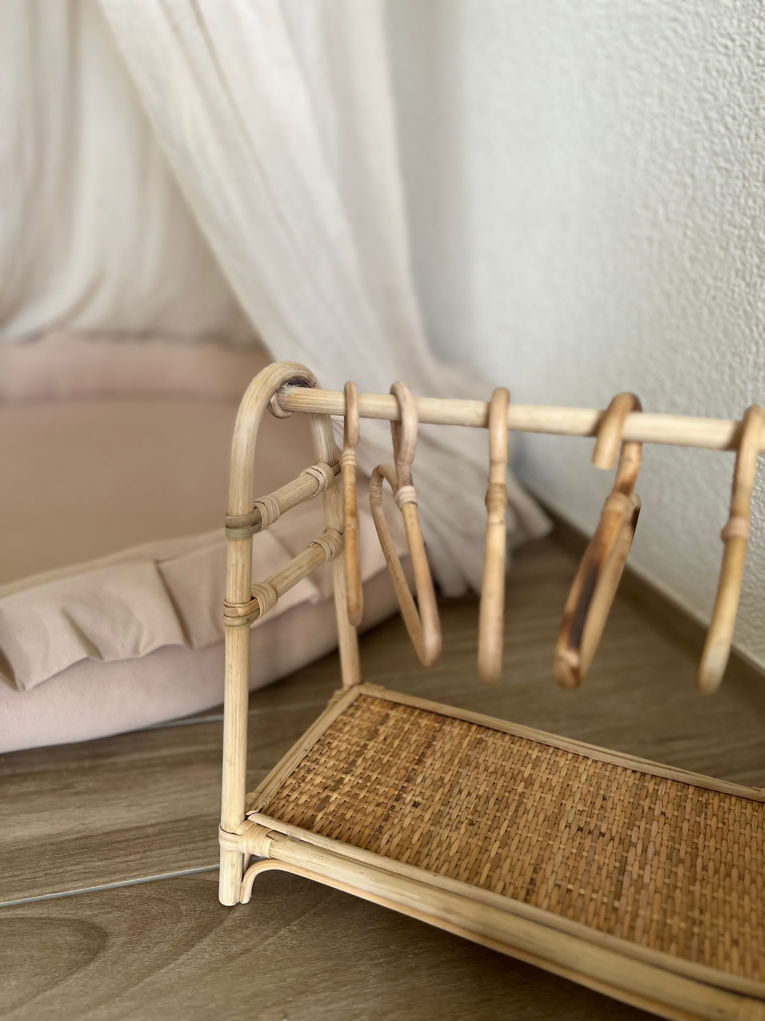 Kleiner Rattan-Kleiderständer mit Bügeln vor einem Kissen