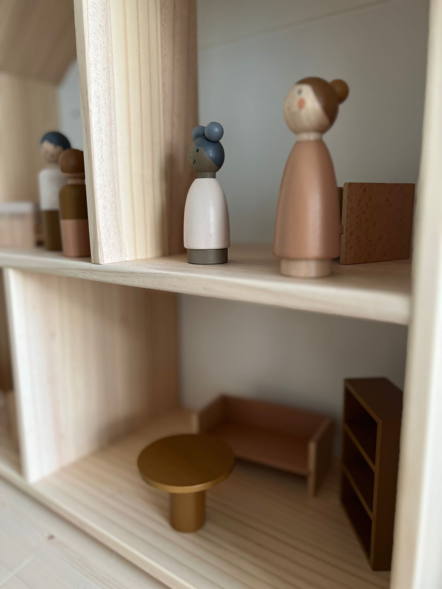 Holzfiguren und Möbel in einem Puppenhaus-Regal
